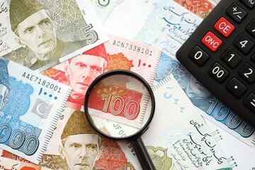Pakistan rupees banknotes and calculator with magnifying glass. Pakistan money bills calc with loupe