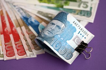 Pakistan rupees banknotes on purple background. The current Pakistan money bills