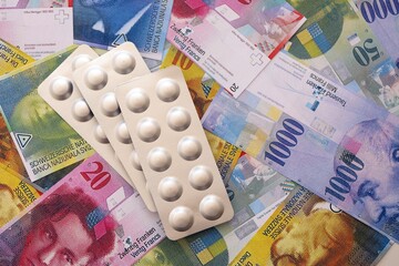 Swiss franc banknotes and medicine pills. The current francs money bills and drugs lies on table