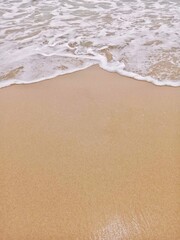 The impact of the water hitting the edge of the beach causes the formation of white foam.
