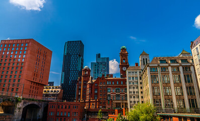 A panorama view over the River Medlock towards  buildings with contrasting architecture styles  in Manchester,UK in summertime
