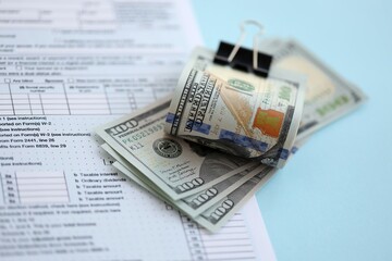 Big amount of United States USD dollar bills on table with 1040 tax return form