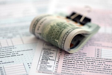 Big amount of United States hundred dollar bills on table with tax return form close up