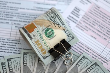 Big amount of United States dollar bills on table with tax return form close up