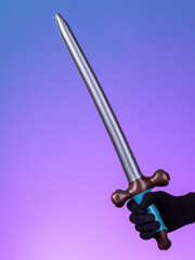 Close-up of a silver inflatable katana toy on a purple and blue background