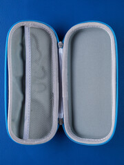 Close-up of a gray school pencil case in a hard format on a blue background
