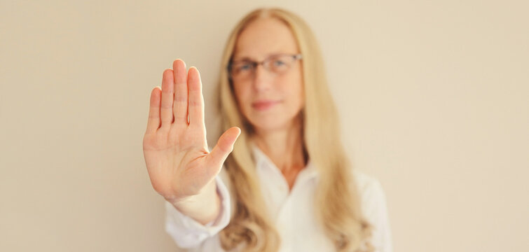 Woman shows stop, no or enough sign with palm of hand, refusal gesture, domestic violence