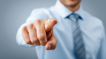 A man in a blue shirt pointing directly at the camera, conveying authority and engagement in a business setting.