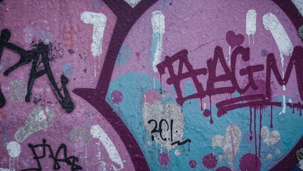 Part of urban graffiti designs on a vintage wall embellished with colorful paint spots in street art fashion. Purple-toned textured surface.