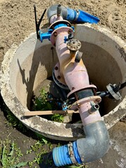 Close up of industrial water pump system with pipes and valves, installed in a protective concrete housing, ensuring efficient water supply and resource management
