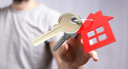 Person offering house keys, symbolizing homeownership, real estate, and new beginnings.
