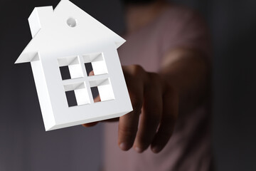 Hand reaching for a white house model.  Real estate, homeownership concept.