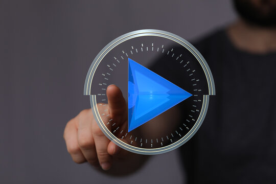 Close-up of a finger pressing a futuristic play button.  Digital interface, technology, media.