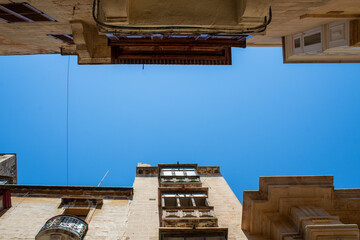 view of blue sky between houses on narrow historic street of island of malta city of valetta