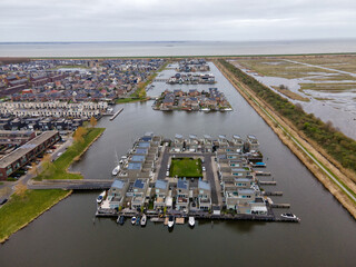 Aerial view of modern floating houses with solar panels and boats, nestled in the tranquil water near the coast, Almere, Flevoland, Netherlands.