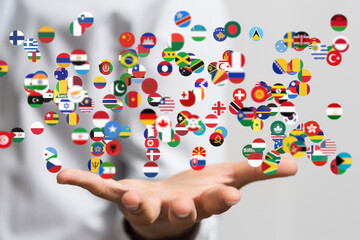 Image of many national flags floating above a hand, representing global connections and international relations.