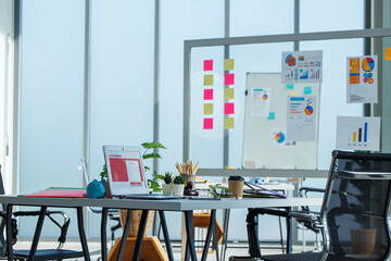 Modern business workspace with laptops, coffee, and colorful charts on desks. Creative corporate environment ready for strategic meetings and team collaboration.