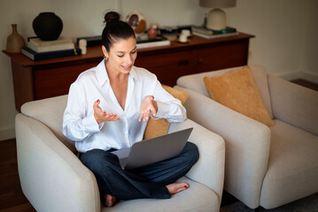 Middle aged woman with her laptop sitting at home and having online meeting