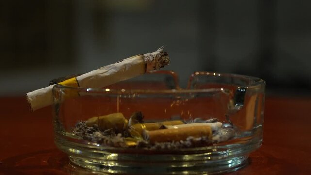 Burning cigarette resting on a glass ashtray