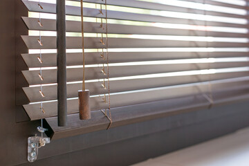 Close-up of wooden blinds with 25mm slats and cable fixing to the window sash. Warm-toned wood finish and precise detailing of natural material blinds highlight elegance and functional sun control.