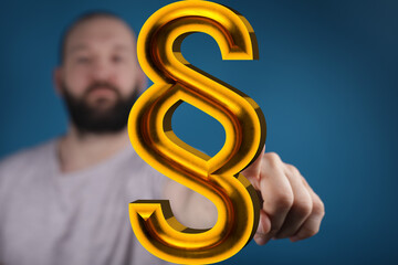 Stock photo of a man interacting with a 3D golden paragraph symbol, representing law, legal...