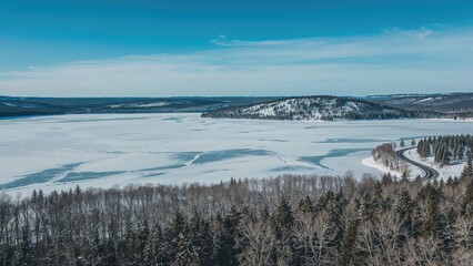 Expansive frozen water body captured from above amidst dense trees