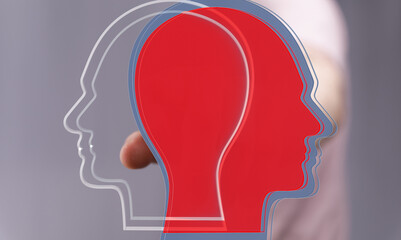 Stock photo depicting two overlapping head profiles, one red, one translucent, symbolizing duality...