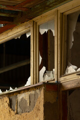 There is an old building that features a broken window as well as a damaged wall in disarray,...