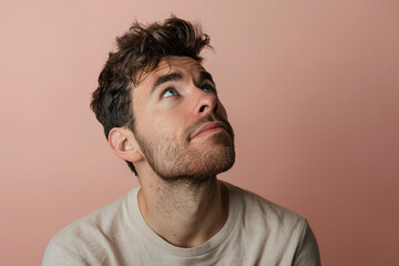 Fototapeta premium Thoughtful man in his 30s gazing upward with hopeful and inspired facial expression