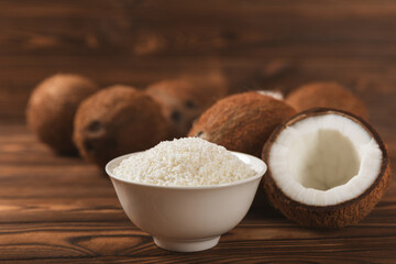 Set of fresh whole and half coconuts and slices on wooden background. Coconut flakes. Vegan. Tropical nut, fruit. Place for text. Copy space.