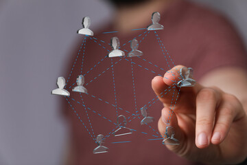 Image of a hand interacting with a network of interconnected people, symbolizing teamwork,...
