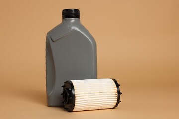 Motor oil in plastic canister and filter on beige background, space for text