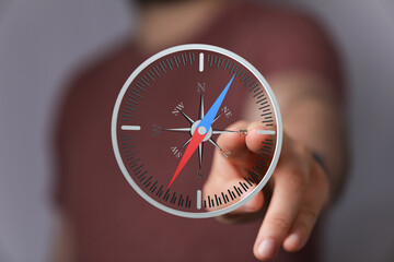 Hand pointing at a digital compass screen, indicating direction and guidance. Ideal for navigation,...
