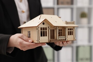 Real estate agent holding house model in office, closeup