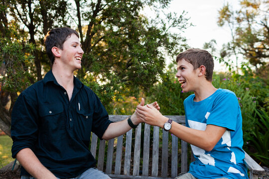 Happy smiling brothers playing hand slapping game outside in backyard