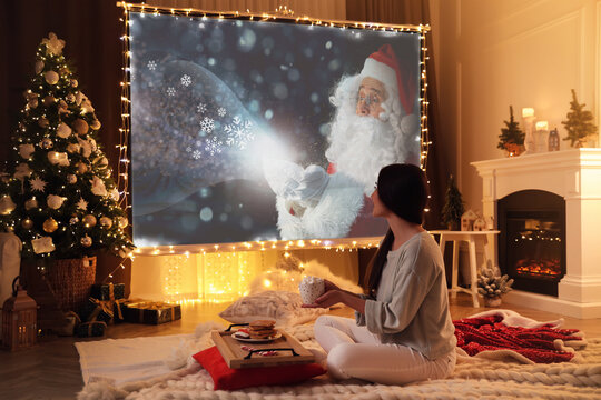 Woman watching Christmas movie using video projector at home
