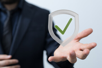 Image of a businessman holding a digital shield with a check mark, symbolizing security and...