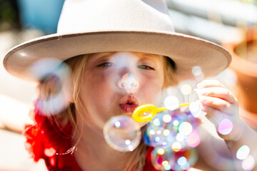 Child playing outside blowing bubbles in sparkling light