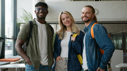 Group of diverse college friends standing together in university hallway smiling at camera cheerful...