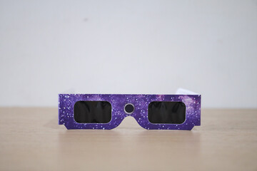 Sun or solar eclipse filter glasses. Paper glasses with solar filters for lenses, and pointing to...