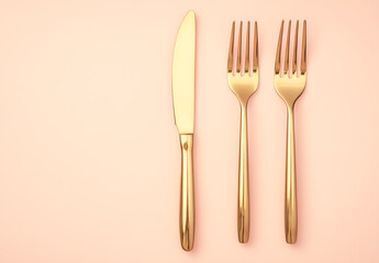 A golden knife, fork, and cutter rest elegantly on a pastel background, casting soft shadows with realistic lighting that enhances their shine.