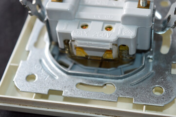 back side of electrical wall switch with visible wiring contacts and metal mounting frame, detailed close-up on black background