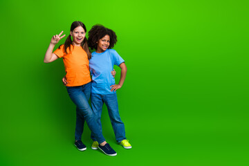 Fototapeta premium Cheerful girls posing against a vibrant green background showcasing friendship, happiness, and casual fashion