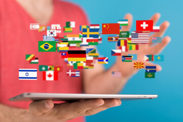 Person using tablet displaying flags of various countries.  International communication concept.