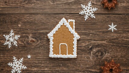 Festive gingerbread house cookie made at home displayed on wooden backdrop
