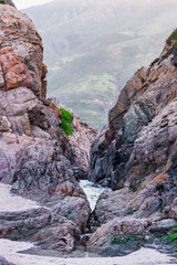 Scenic coastal view at Garrapata State Park near Big Sur, California, showcasing rugged cliffs, vibrant plants, and the Pacific Ocean along the iconic Highway 1 on a clear spring day