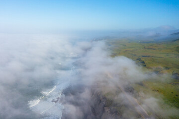 Aerial view of mist rolling over lush green hills along Highway 1 near Scott Creek Beach in...