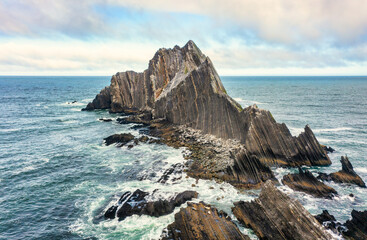 Aerial view of San Pedro Rock off the California coast near Pacifica. Sharp striated cliffs rise...