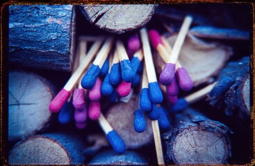 Colorful matches arranged among wooden sticks in a close-up view showcasing their vibrant tips and natural earthy background