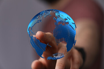 Hand touching a digital globe, representing global connection and technology.